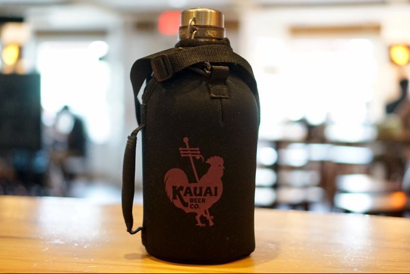 Black neoprene growler koozie with carrying strap on a bar